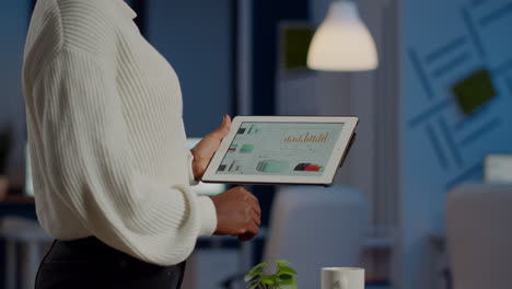 african freelancer woman holding tablet checking financial graphs