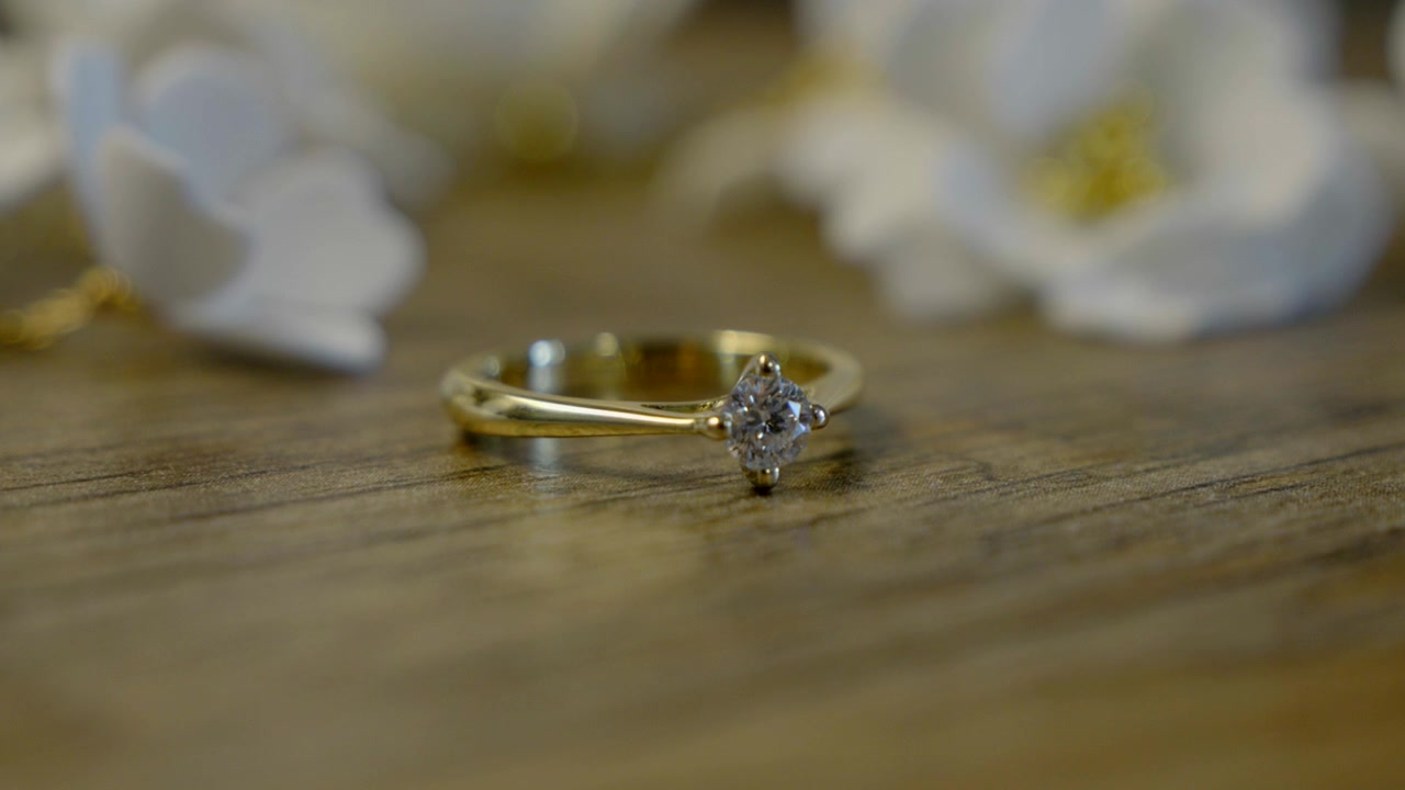 Primer plano de un hermoso anillo de compromiso sobre una mesa con un fondo floral