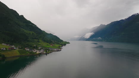Stunning-aerial-over-norwegian-fjord,-farmland-and-homes-on-hillside