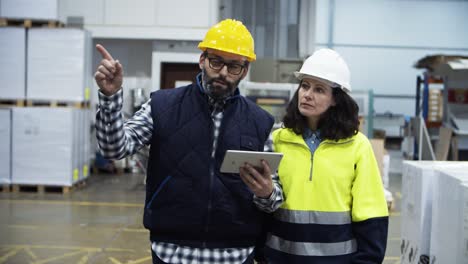 Vorderansicht-Von-Zwei-Fabrikarbeitern,-Die-Mit-Einem-Tablet-Im-Werk-Gehen