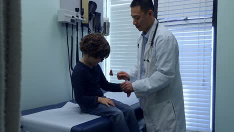 side view of young asian male doctor examining caucasian boy patient hand in a clinic 4k