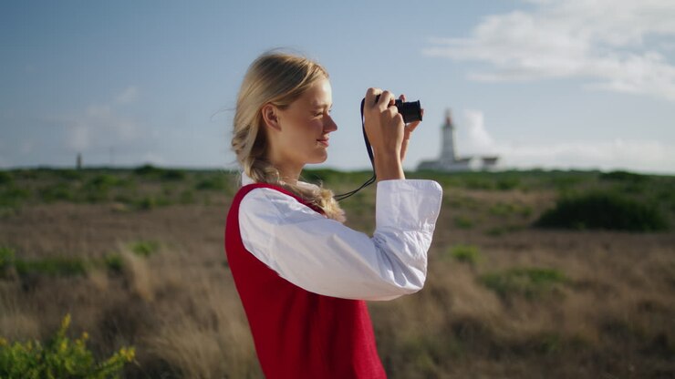 Positive photographer shooting nature closeup. Vertically woman squinting at sun