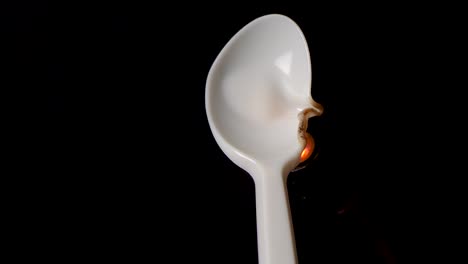 Flame-melts-plastic-spoon-in-front-of-black-background