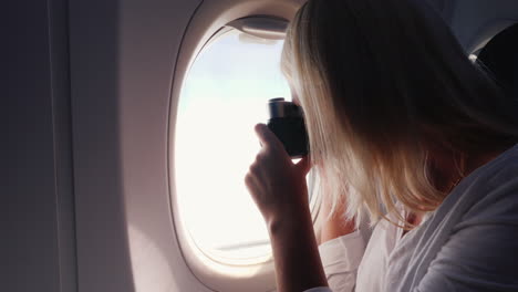 Eine-Frau-Fotografiert-Eine-Schöne-Aussicht-Aus-Dem-Fenster-Eines-Flugzeugs