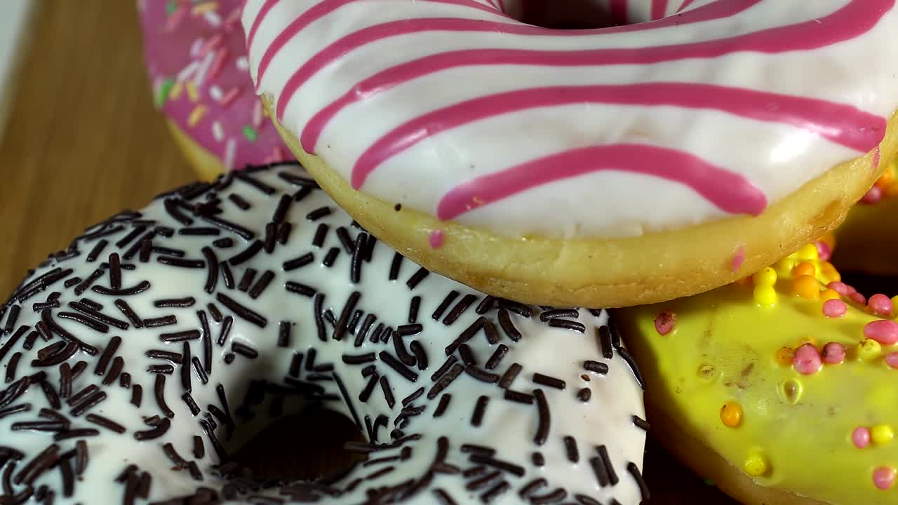 rosquillas giratorias con diferentes rellenos en la mesa. deliciosa rosquilla dulce girando en un plato. rosquilla brillante y colorida macro disparo de primer plano girando sobre un fondo blanco. bucle sin costuras.