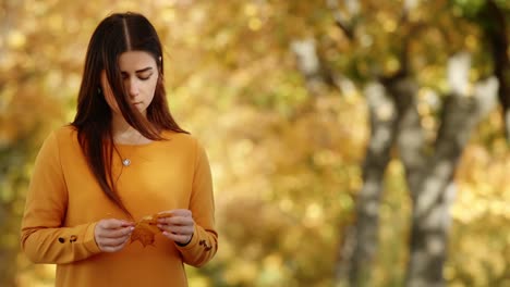 Girl-walking-during-autumn-fall-holding-leaf