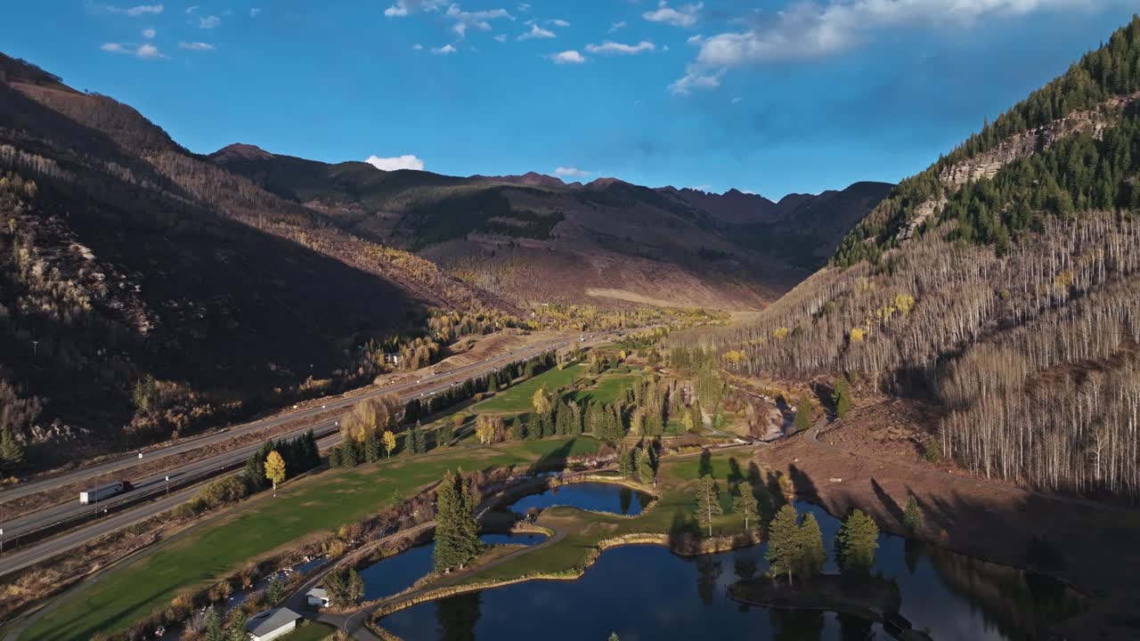 Aerial drone pullback over a peaceful valley surrounded by mountains and trees in Vail, Colorado