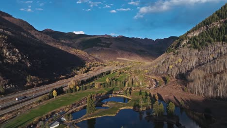 aerial drone pullback over a peaceful valley surrounded by mountains and trees in vail, colorado
