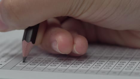 student hand filling out in answer sheet with standardized test form