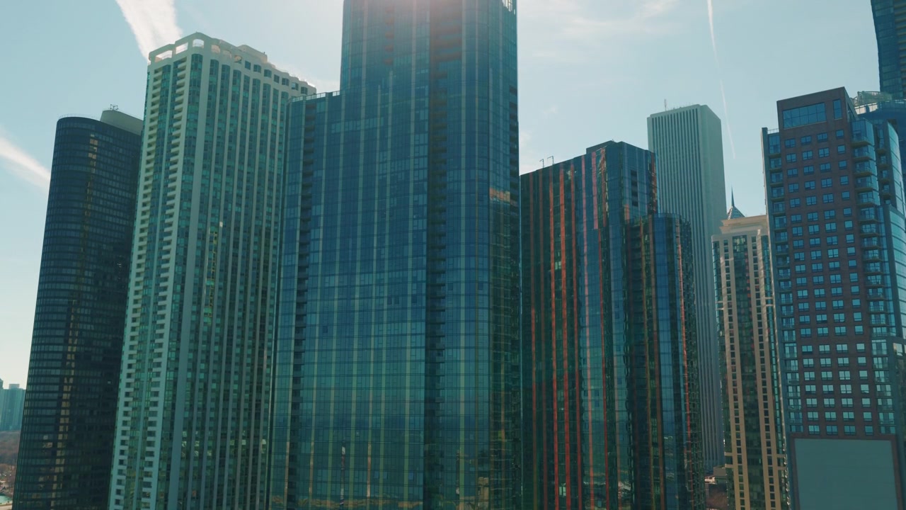 Arrancacéus de vidro imponentes do centro de Chicago sob um céu azul claro, simbolizando sucesso corporativo e crescimento urbano. Vista de baixo para cima
