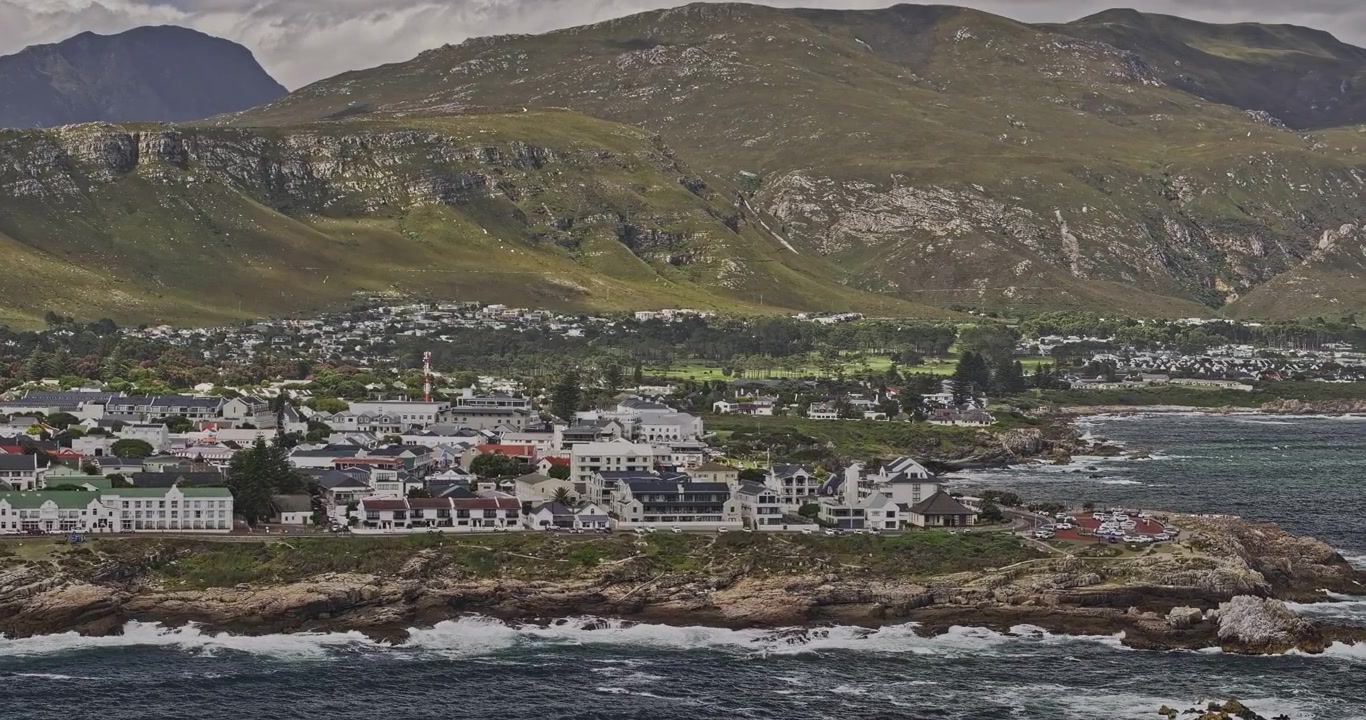 Hermanus, África do Sul, Aérea v15 telefoto, sobrevoo baixo sobre a baía em direção às residências à beira-mar, Gearing's Point e montanhas costeiras - Filmado com Mavic 3 Pro Cine - 8 de janeiro de 2024