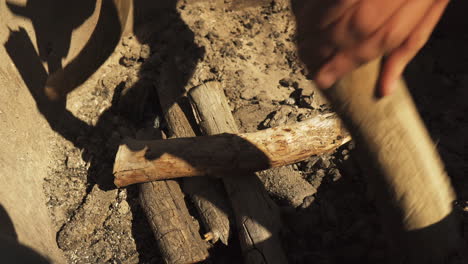 hombre de cerca comenzando a apilar madera en pirámide para fogata