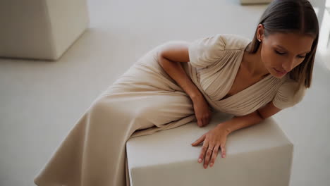 elegant woman in beige dress posing in a minimalist studio