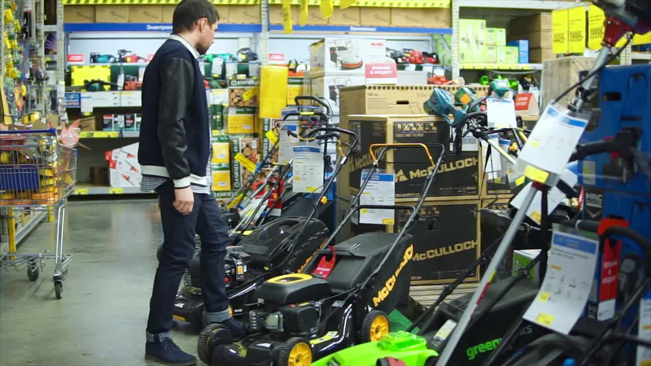 hombre comprando cortadoras de césped en una ferretería