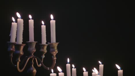 a group of white candles some on a candelabra lit up then blown out by the wind in slow motion