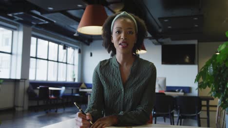 portrait of happy african american businesswoman talking and looking at camera at office