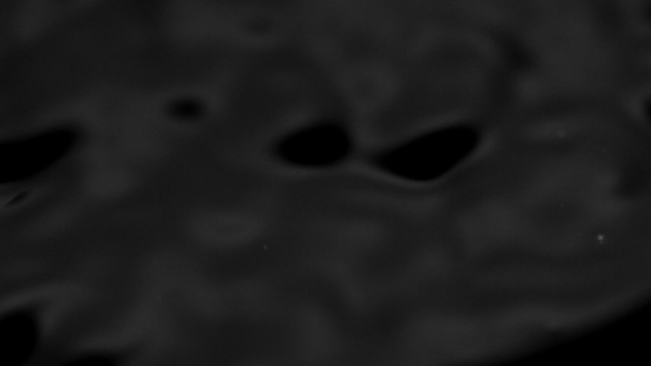 Stænk og dråber på væskens overflade. Abstrakt sort baggrund. Vandvibration. 4K slow motion 100 fps, ProRes 422, 10 bit.