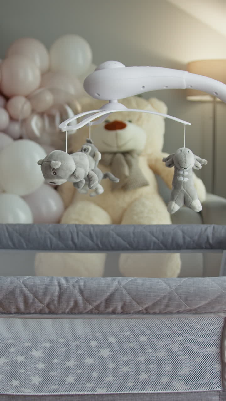 Primo piano di una giostrina per culla con giocattoli di peluche appesi sopra un grande orsetto e colori pastello.
