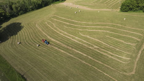 Aerial-View-Of-Tractor-Baler-Working-Over-Fields-After-Wheat-Harvest-In-Summer