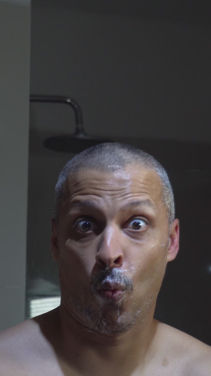 Man Shaving His Face with a Razor in the Bathroom
