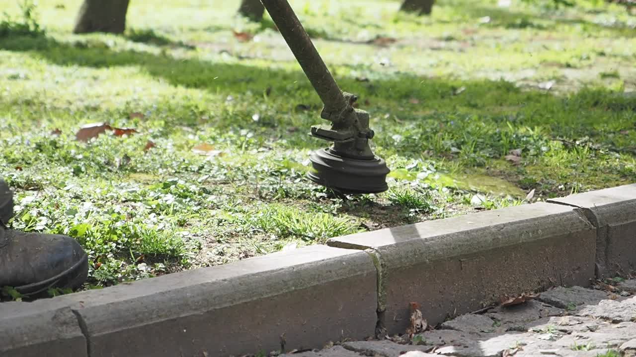hombre cortando el césped a lo largo de la acera