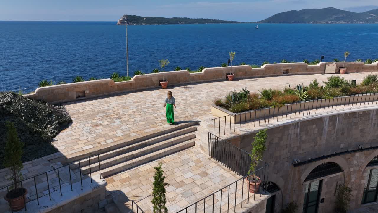 Close drone circling woman walking along overlook of Mamula Island fortress walls and inner courtyard from above