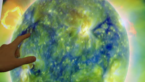 hand pointing at a visualization of the sun's surface