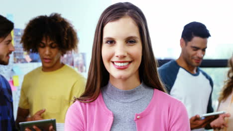 diseñador gráfico sonriente de pie con los brazos cruzados mientras un colega discute