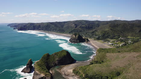 Passing-over-one-of-the-two-rocky-outcrops-on-the-stunning-Piha-Beach,-New-Zealand-on-the-Tasman-Sea