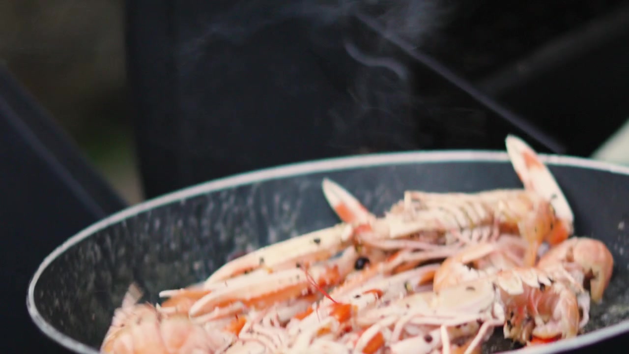 Fresh Langoustines Flipped in Hot Pan in Slow Motion. Shellfish Seafood being Cooked Outdoors. Norway Lobster.