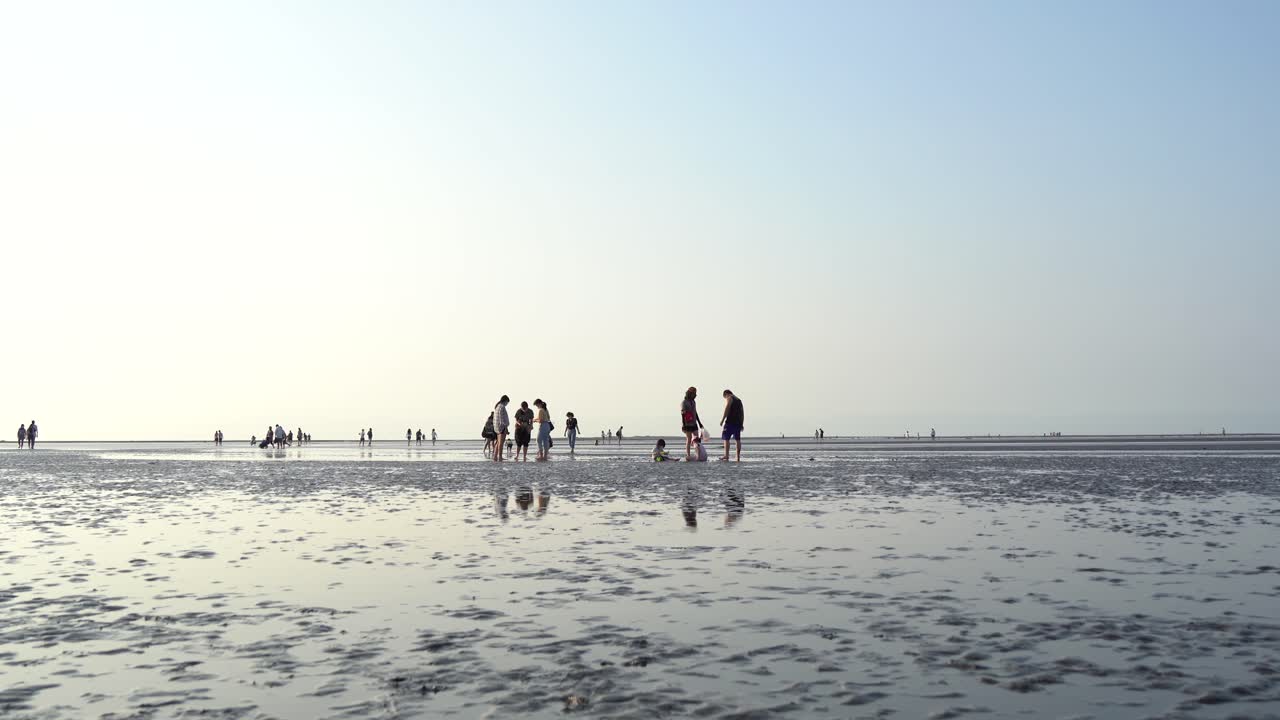 대만 타이중 시의 유명한 원시 가오메이 습지 보호 구역에서 자연을 즐기는 갯벌에서 맨발로 먼 거리의 관광객들과 함께 아름다운 풍경을 포착하는 낮은 각도의 사진