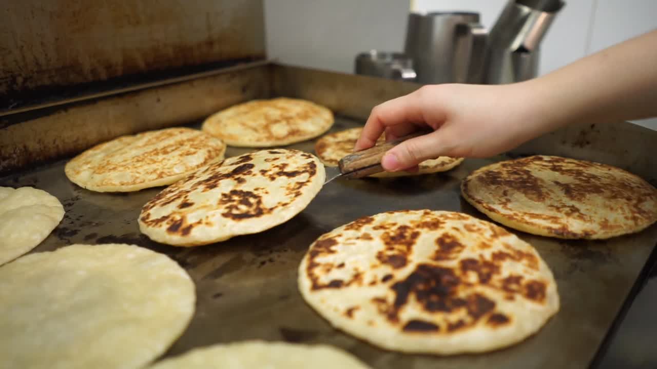 chef profesional cocinando y volteando pan plano indio roti en un plato caliente comercial en la cocina