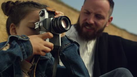 una ragazza carina che usa una fotocamera che scatta foto in famiglia in vacanza in spiaggia all'aperto.