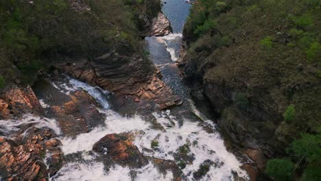 cataratas dos couros in brazil, in chapada dos veadeiros national park, showcasing a powerful waterfall cascading over rugged rocks, surrounded by lush greenery, drone overhead flying