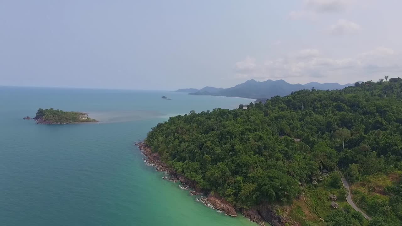 drone de isla tropical transportando a la izquierda tiro de islas con exuberante selva tropical y palmeras tropicales con playa de arena blanca y costa rocosa