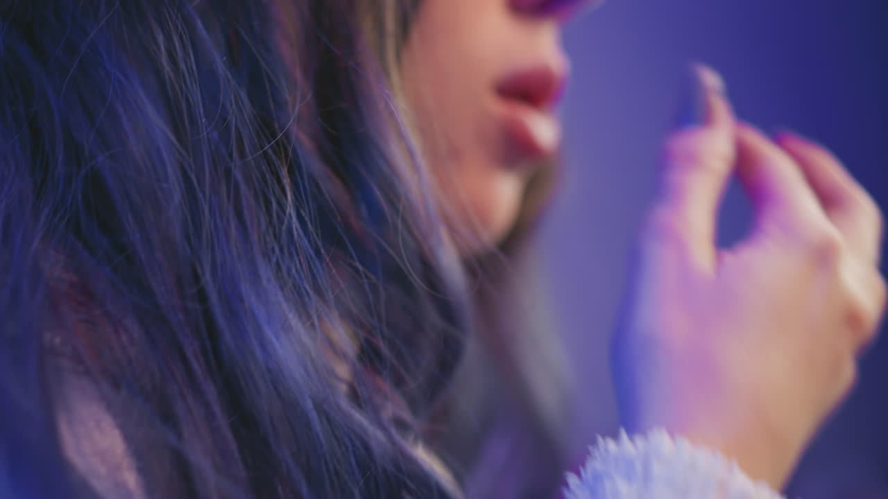 Close up of woman reaching into popcorn bowl while dusting hand beside condenser microphone in creative studio setup, cozy sweater visible with warm ambient lighting in background