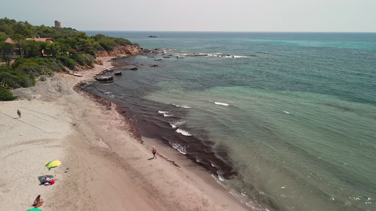 mar azul y playa con turistas disfrutando de las vacaciones de verano en cerdeña, italia - retroceso aéreo