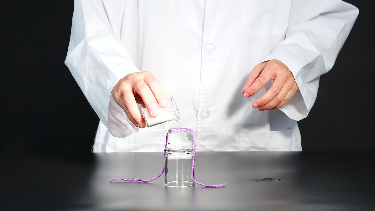 A scientist demonstrates a chemical reaction using ice, salt, and string, showcasing a fascinating freezing process