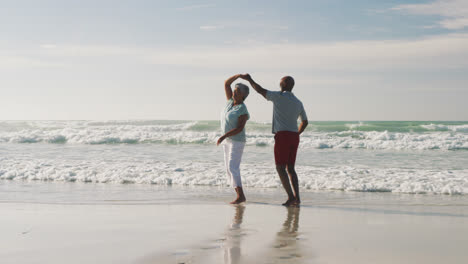 Pareja-Afroamericana-Senior-Sonriendo-Y-Bailando-En-La-Playa