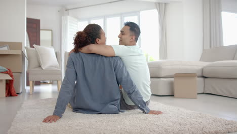 Happy-diverse-gay-male-couple-in-new-home,-sitting-embracing-in-living-room,-copy-space,-slow-motion