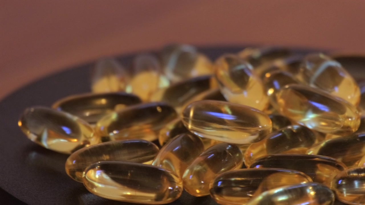 Super slow motion di capsule dorate che ruotano su una superficie scura