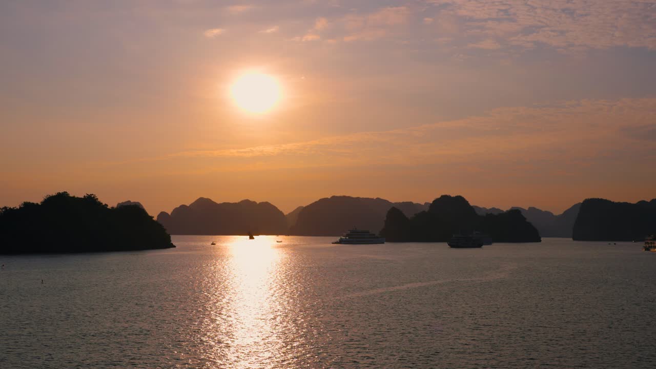 Sun Rising Above Karst Mountains in Silhouette at Ha Long Bay with Many Cruise ships touring, Vietnam
