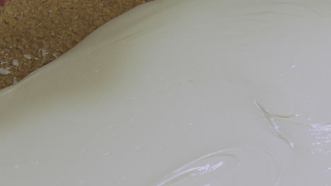 top down view of a worker spreading soft icing on top of a tray of flap jack