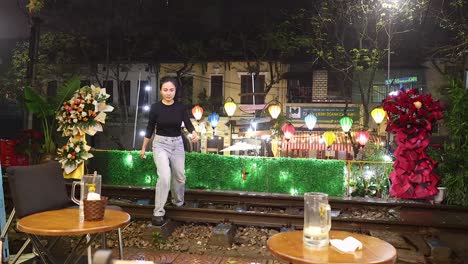 mujer caminando cerca de las vías del tren decoradas por la noche