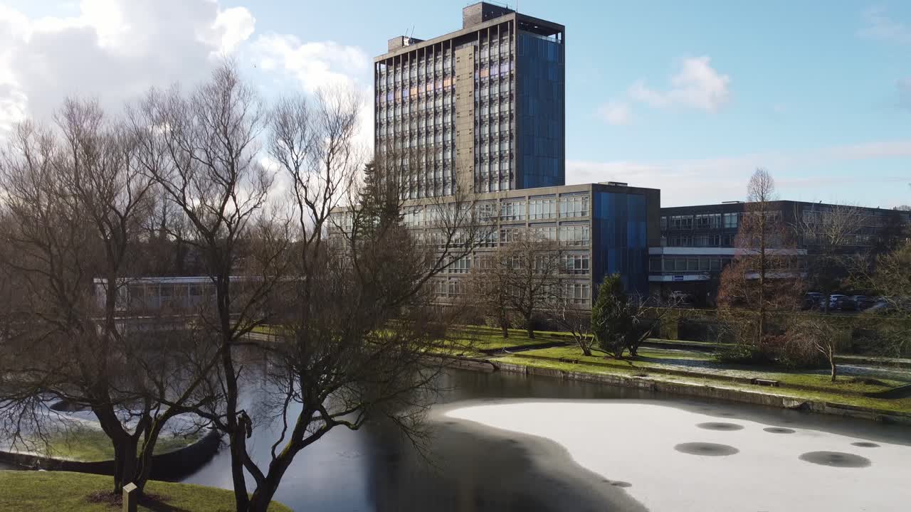 Sede centrale in vetro di Pilkingtons, grattacielo blu per uffici commerciali, discesa verso i terreni del parco innevati, vista aerea.