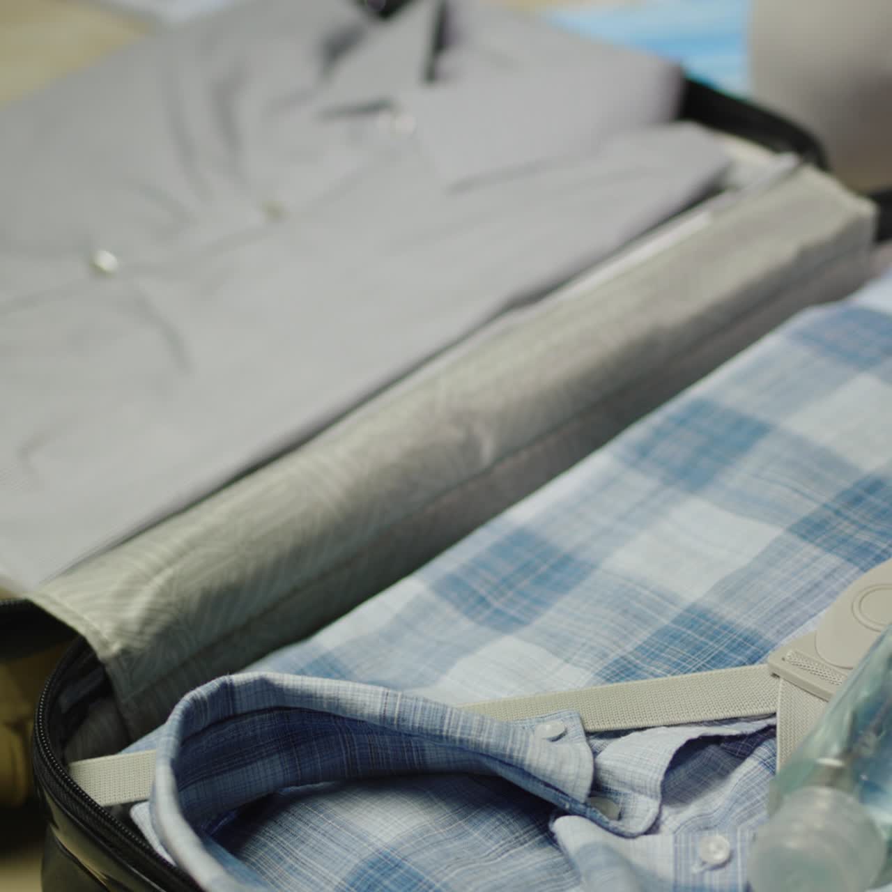 Man puts clothes, protective masks and antiseptic in a suitcase