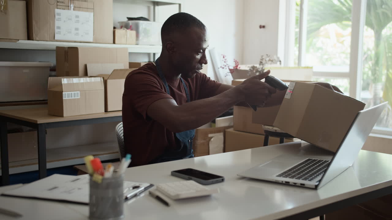 Black Manager Checking Parcels with Scanner in Storage Office