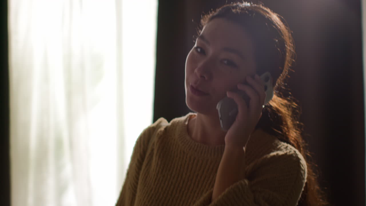 쇼핑을 마치고 집으로 돌아오는 여성이 드폰으로 얘기하며 어깨에 가방을 고 라운지를 걸어가고 있다.