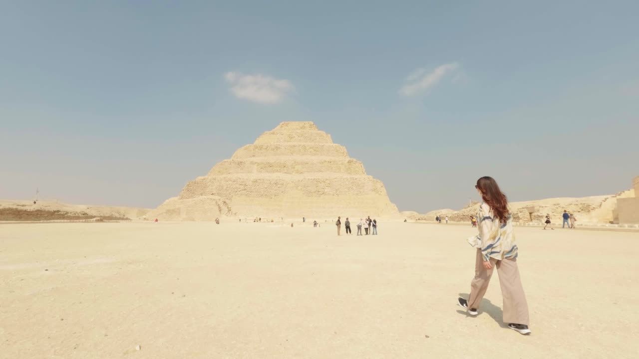 Žena kráčející k starověké Stupňovité pyramidě Džoserově v sakkárské poušti