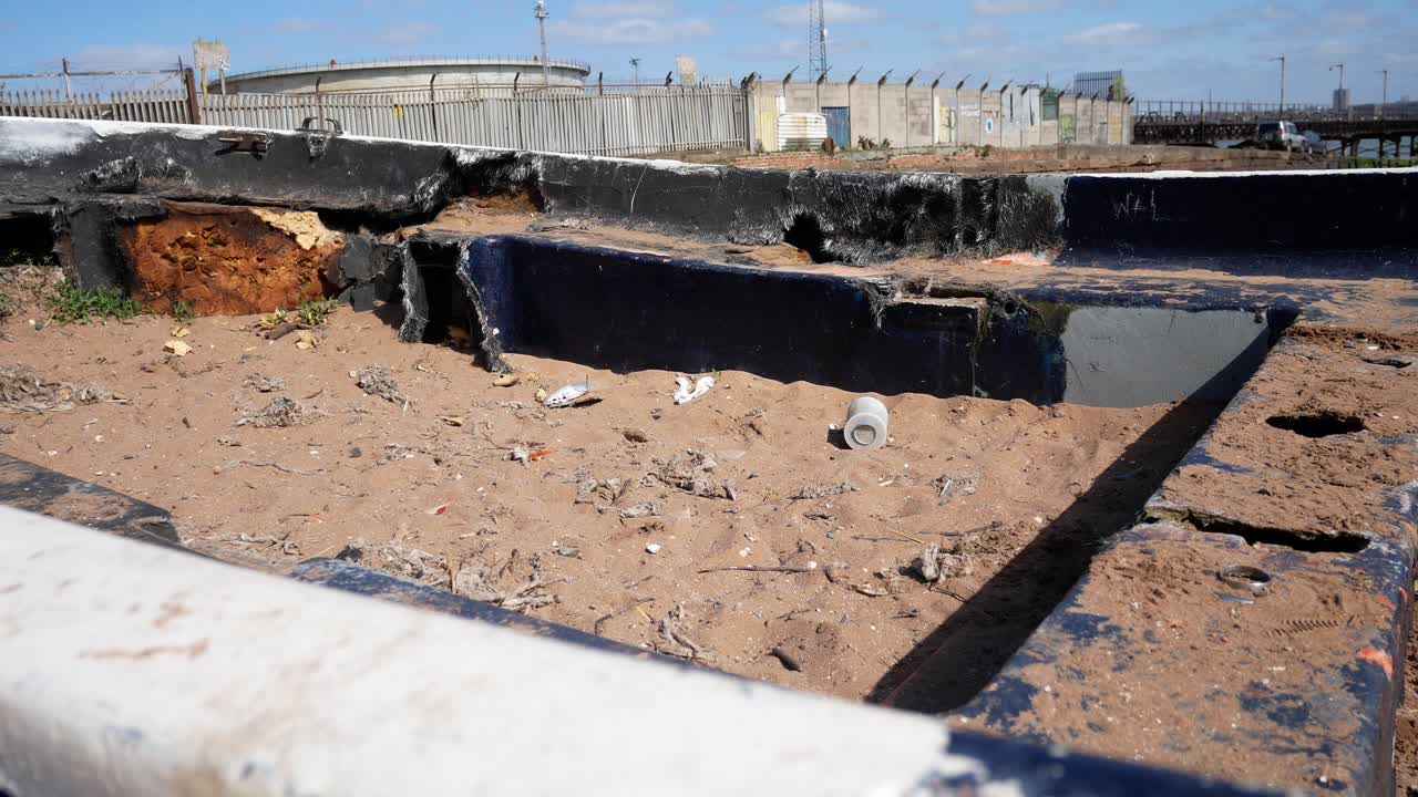 nubes de cielo azul sobre el viejo naufragio abandonado a la izquierda en la ruina de la playa de arena dorada cerca de la costa de la refinería